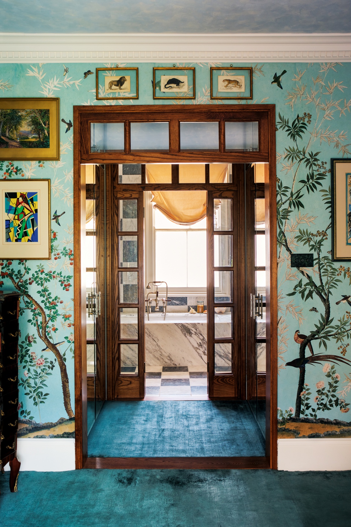 a view through internal glass-paned and wood doors to a bathroom with black and white checkerboard tiles on the floor and walls and a built-in marble bathtub