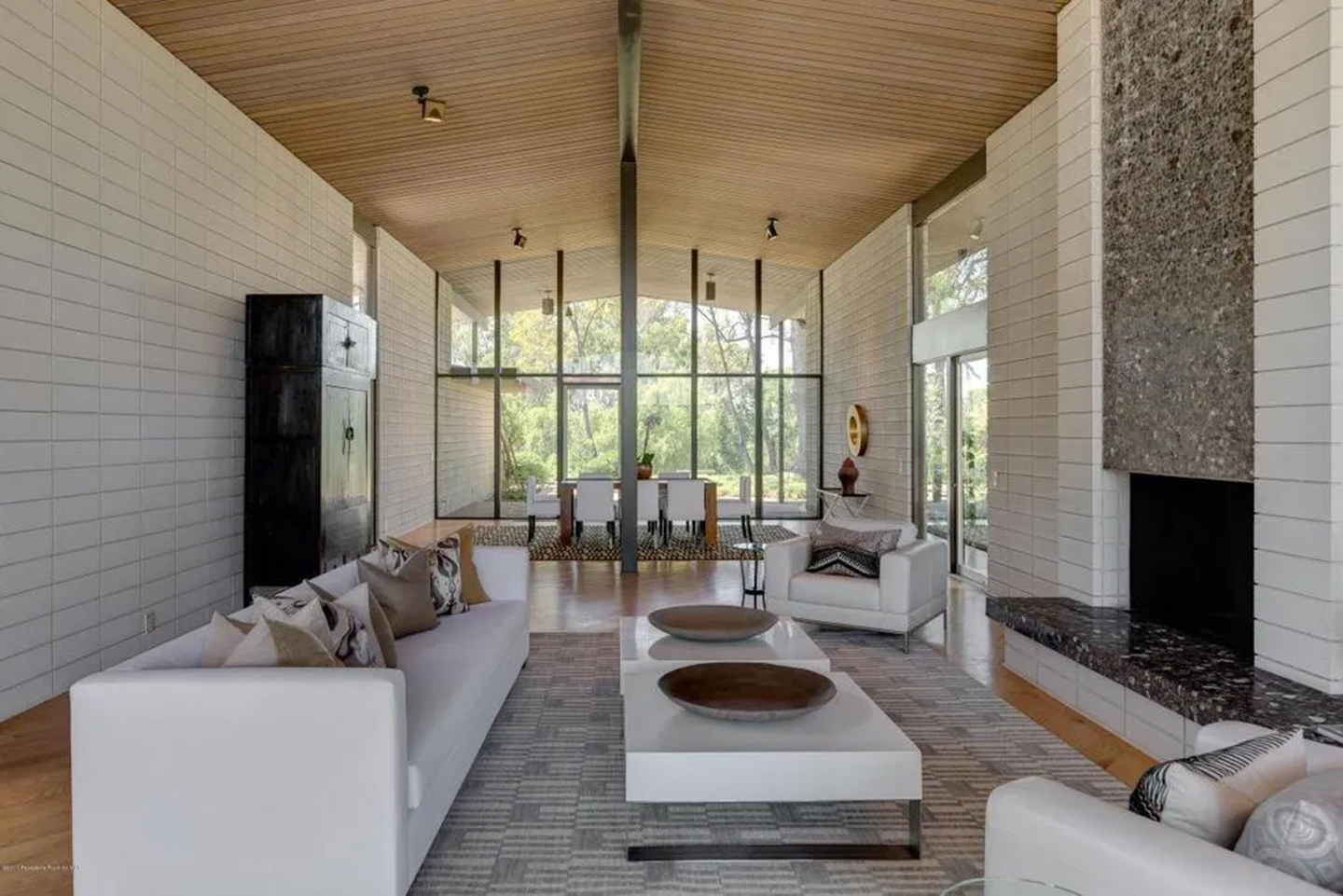 meryl streep's pasadena house, with large glass walls, white tiled walls, a terrazzo fireplace and a modern white sofa