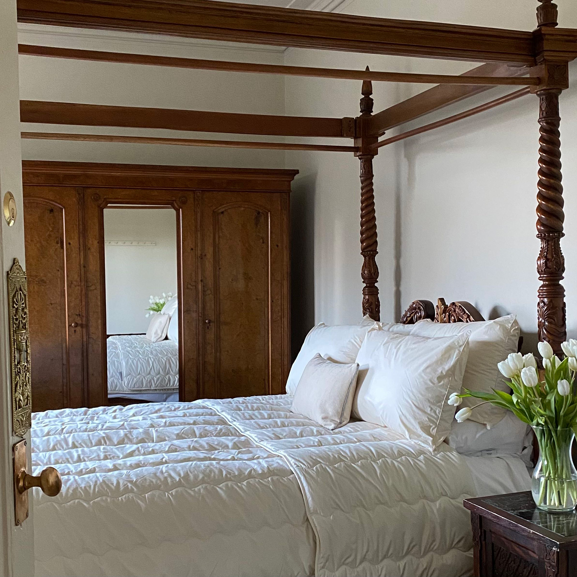wooden four poster bed with white linen