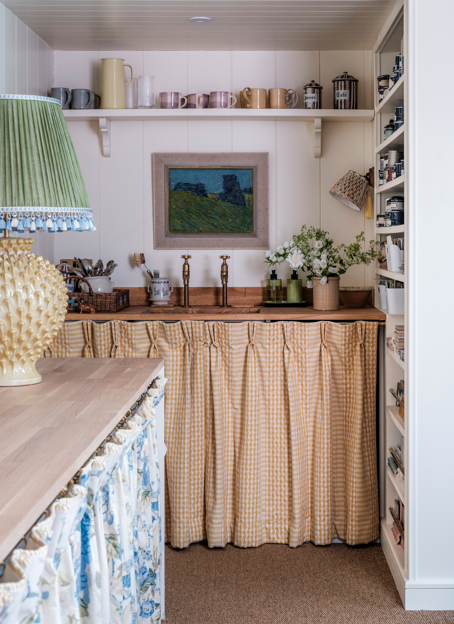 a kitchen sink with a yellow gingham skirt under it, open shelving above it and white vertical wall shelves next to it