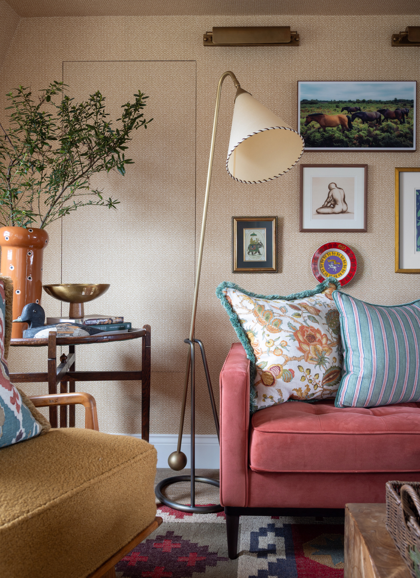 a living room corner wtih a pink sofa and a yellow boucle armchair and a portable floor lamp