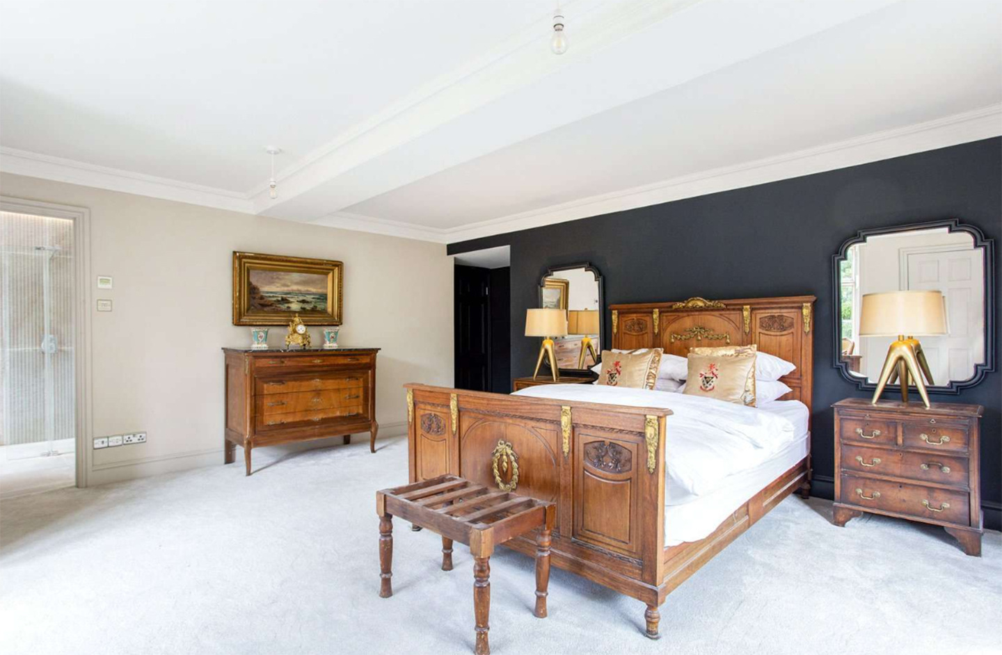 a bedroom with a navy feature wall, a large wooden bed and matching antique wooden furniture