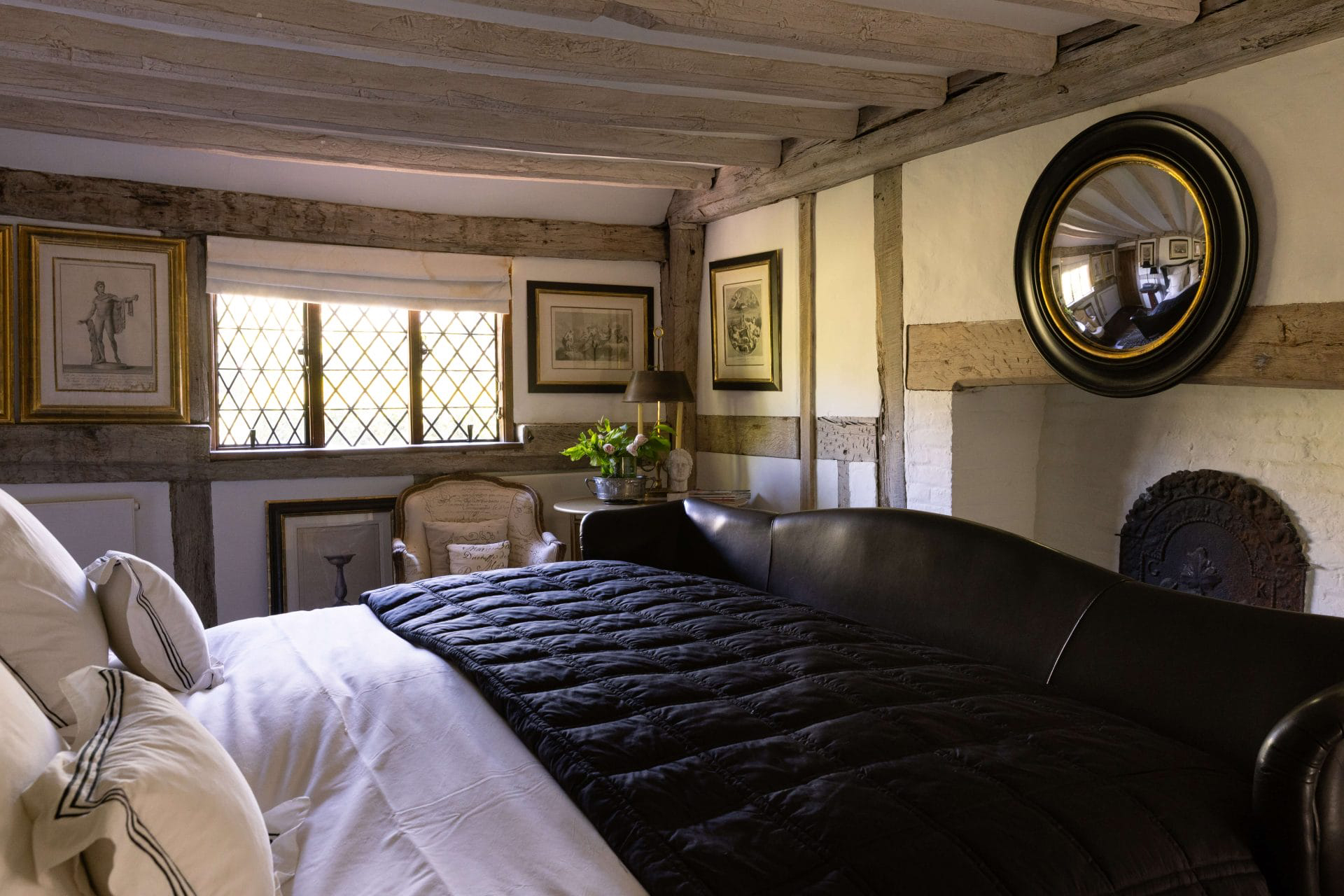 A cottage bedroom with wooden beams and a large black bed, former home of Princess Margaret