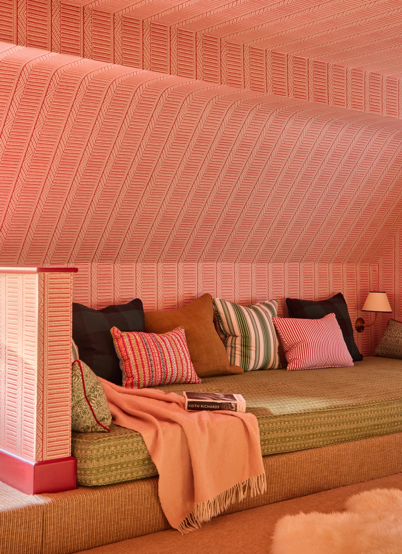 a reading nook with pink and white patterned wallpaper on the ceiling and walls and a built in bench with cushions