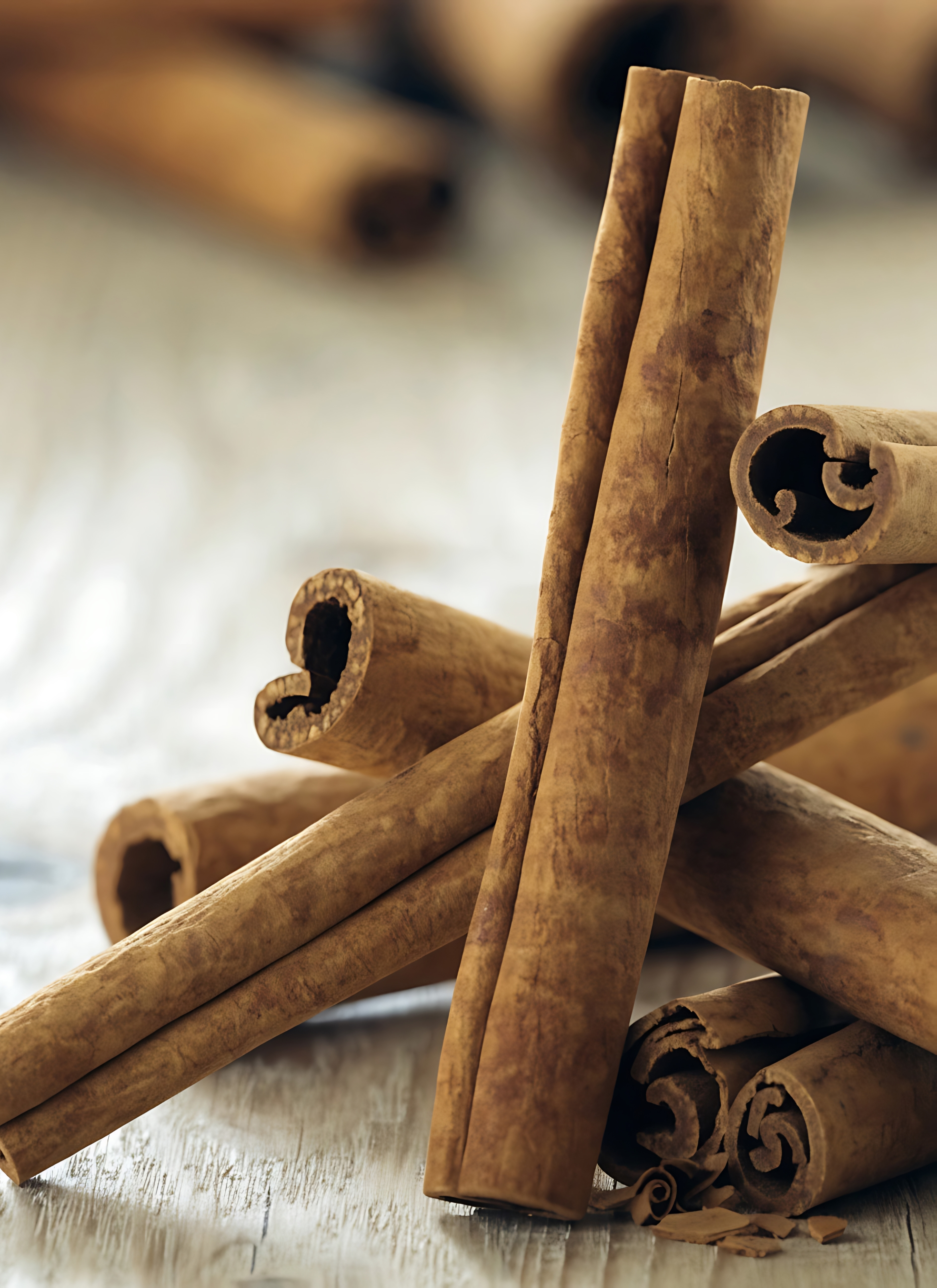 a close up of a stack of cinnamon sticks on a pale wooden table