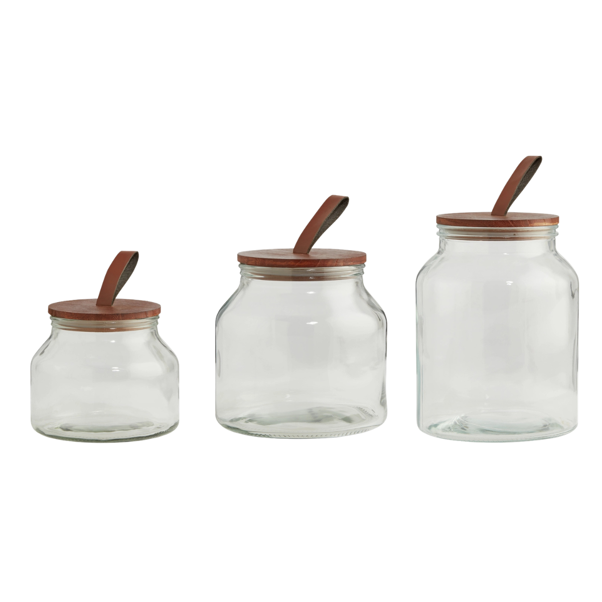 a set of three glass storage jars with leather lids ascending in size