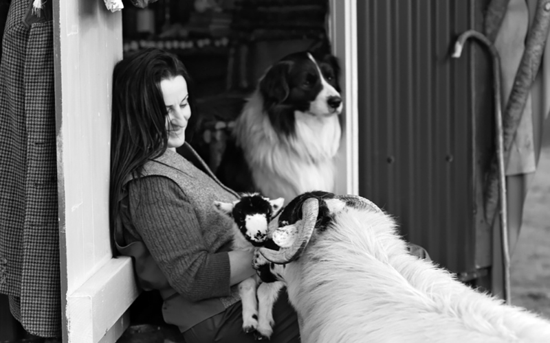 Alison with a lamb and shadow the sheepdog