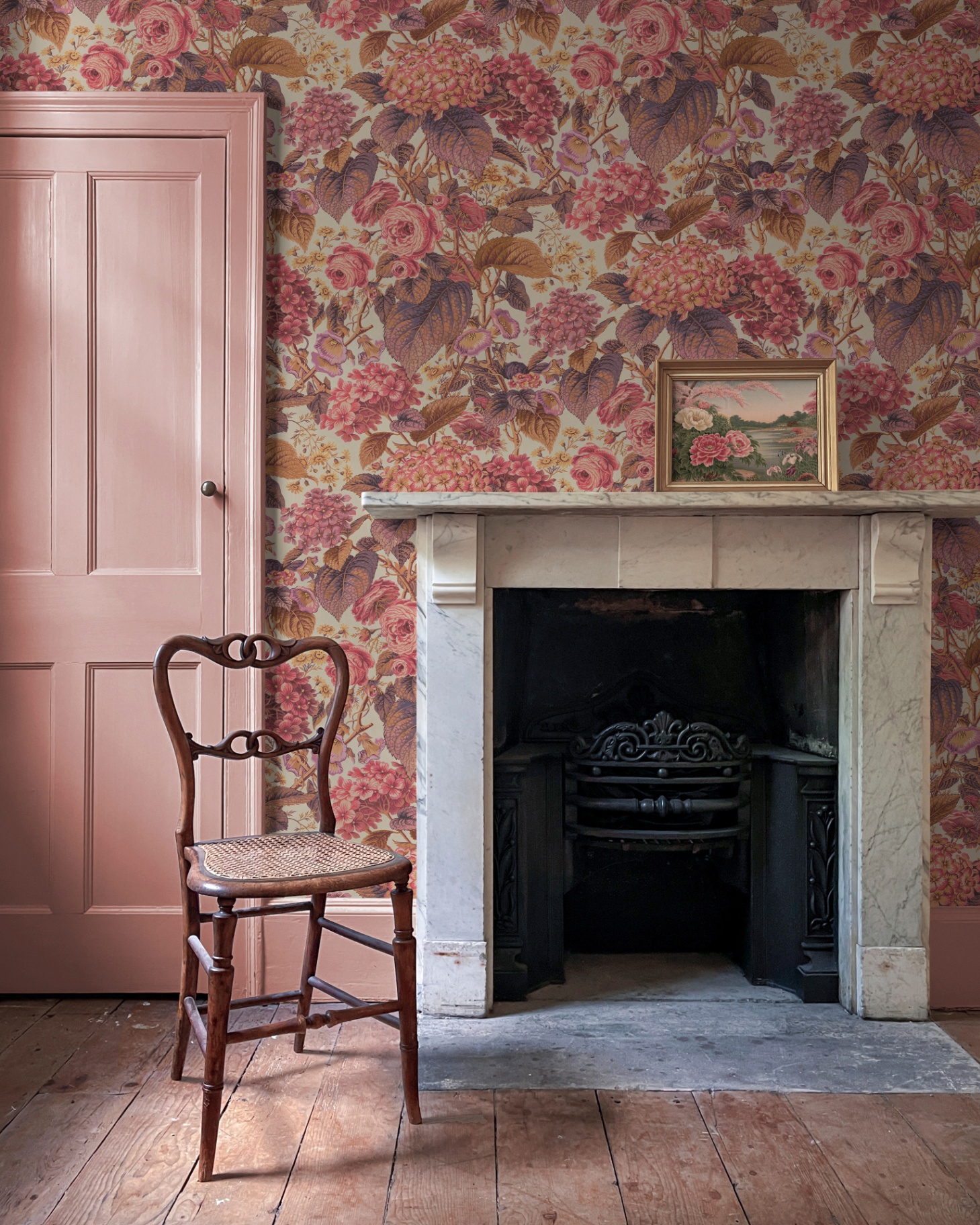 a large marble fireplace, pink floral wallpaper, wooden floor boards, a pale pink door and a wooden dining chair