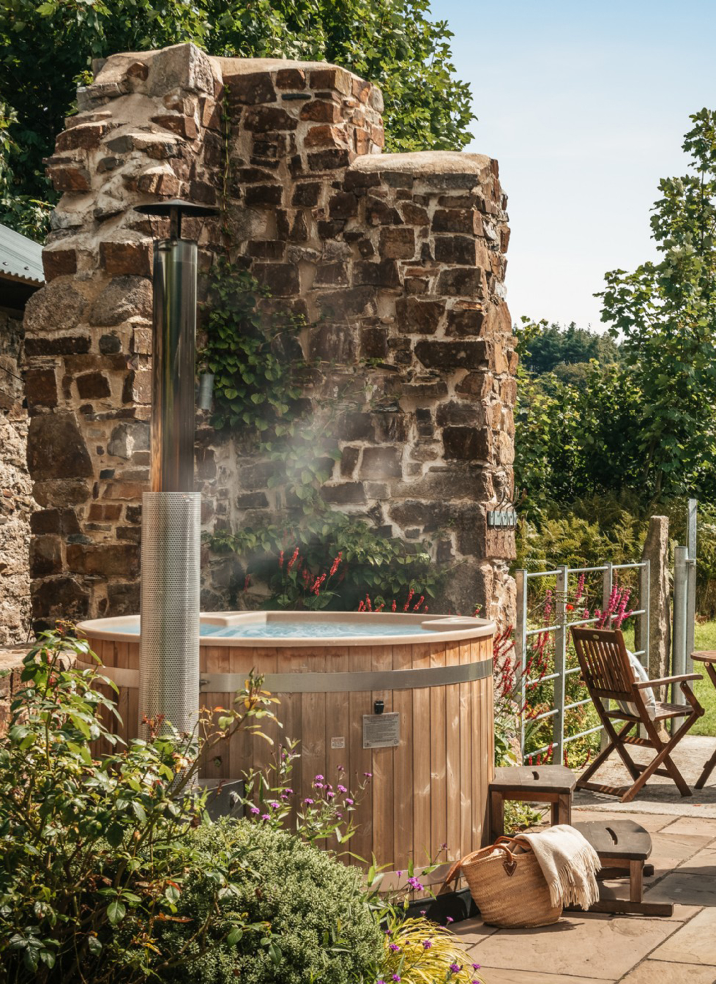 an outdoor wooden hot tub in front of a brick wall