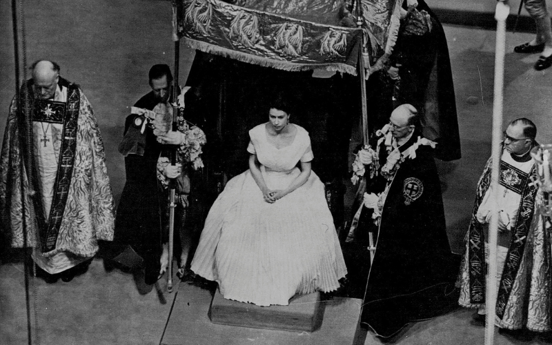 Queen Elizabeth II awaits the anointing ceremony during her Coronation in June 1953, carried out by the Archbishop of Canterbury. She is in a white dress under a canopy
