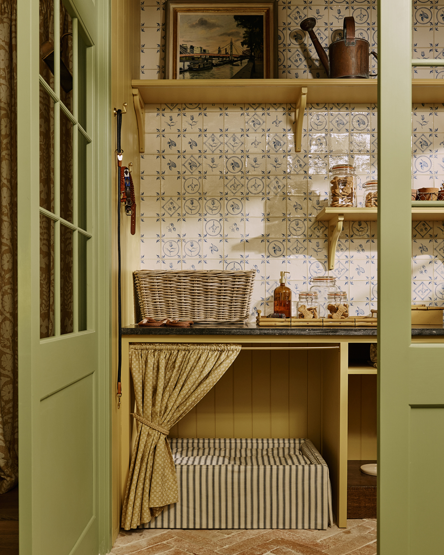 a utility room with a green open door, yellow woodwork and a dog bed alcove with a yellow patterned cafe curtain covering a striped dog bed
