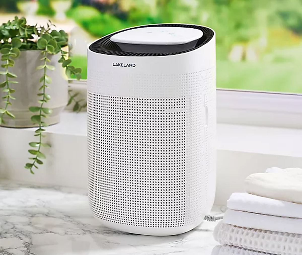 a small white dehumidifier on a white and grey marble countertop in front of a window