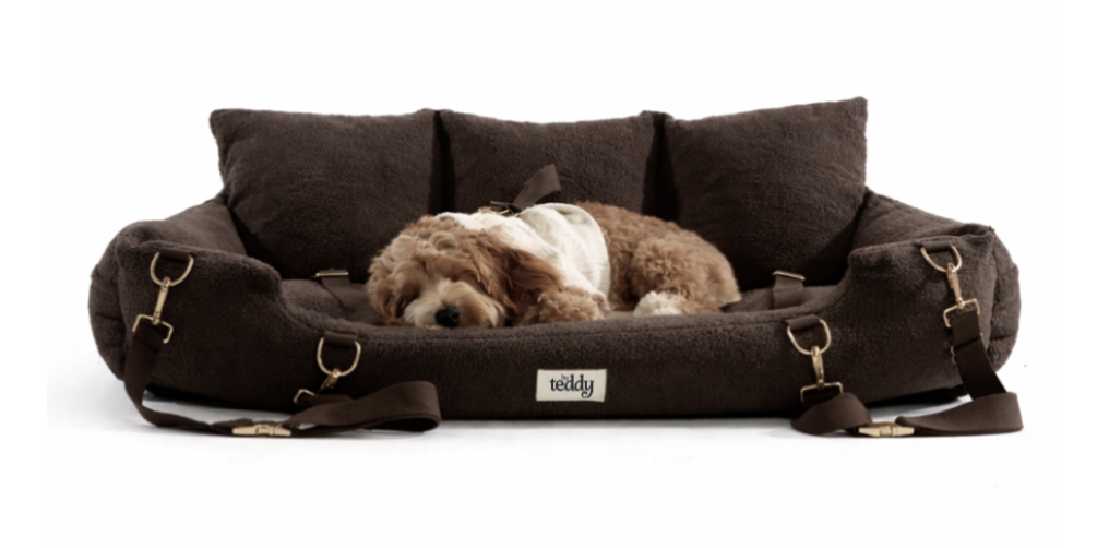 an extra large chocolate brown dog bed pictured with a dog sleeping inside on a white background