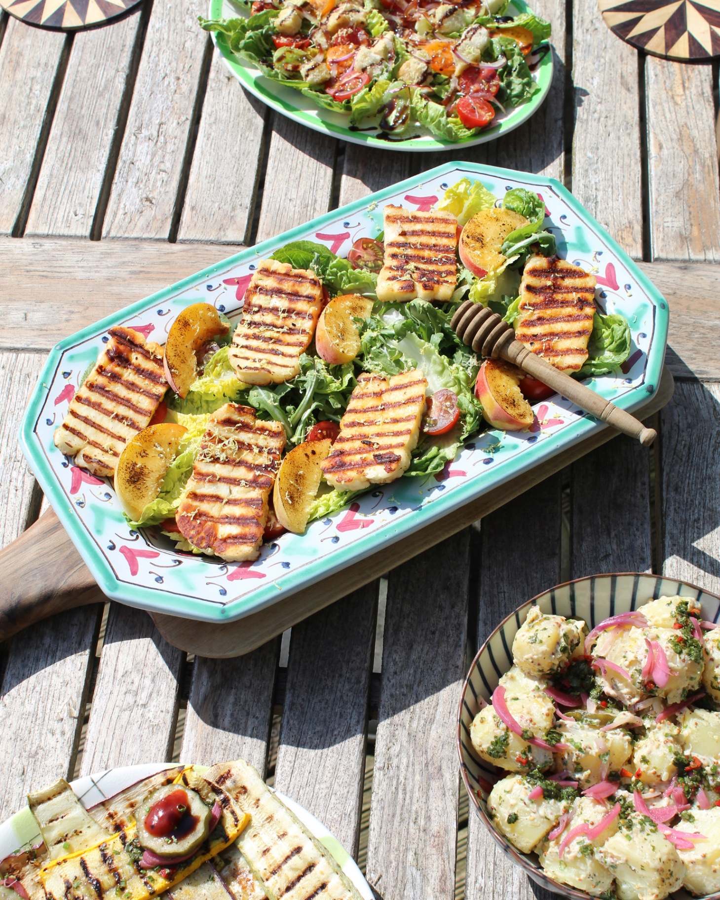 a halloumi and peach salad in a blue and pink patterned platter on a wooden table