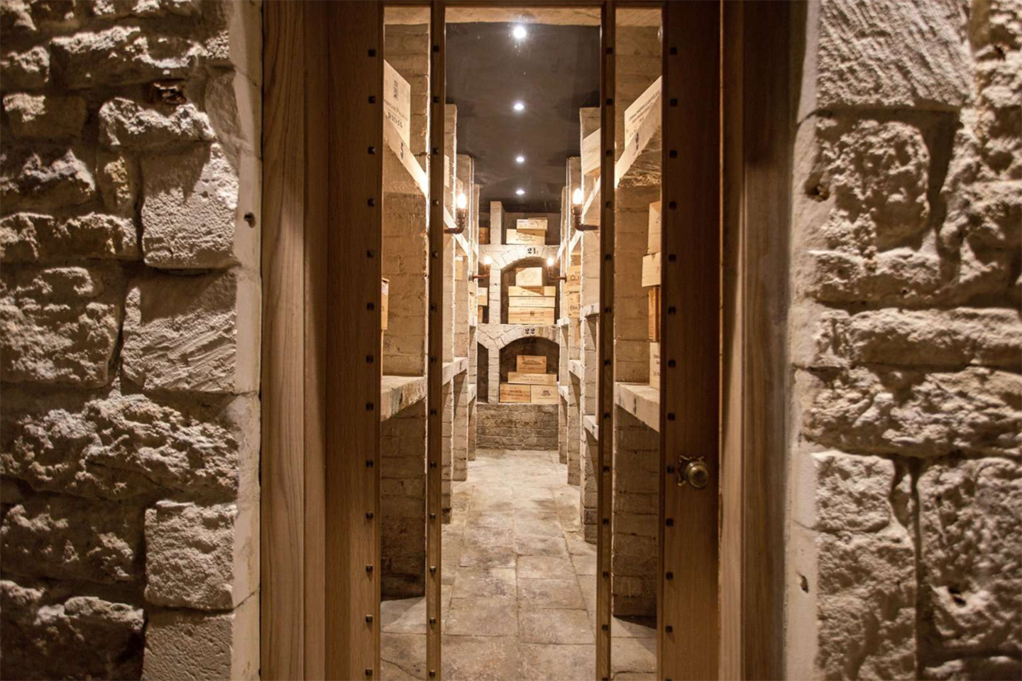 a wine cellar with exposed stone walls and wooden crates