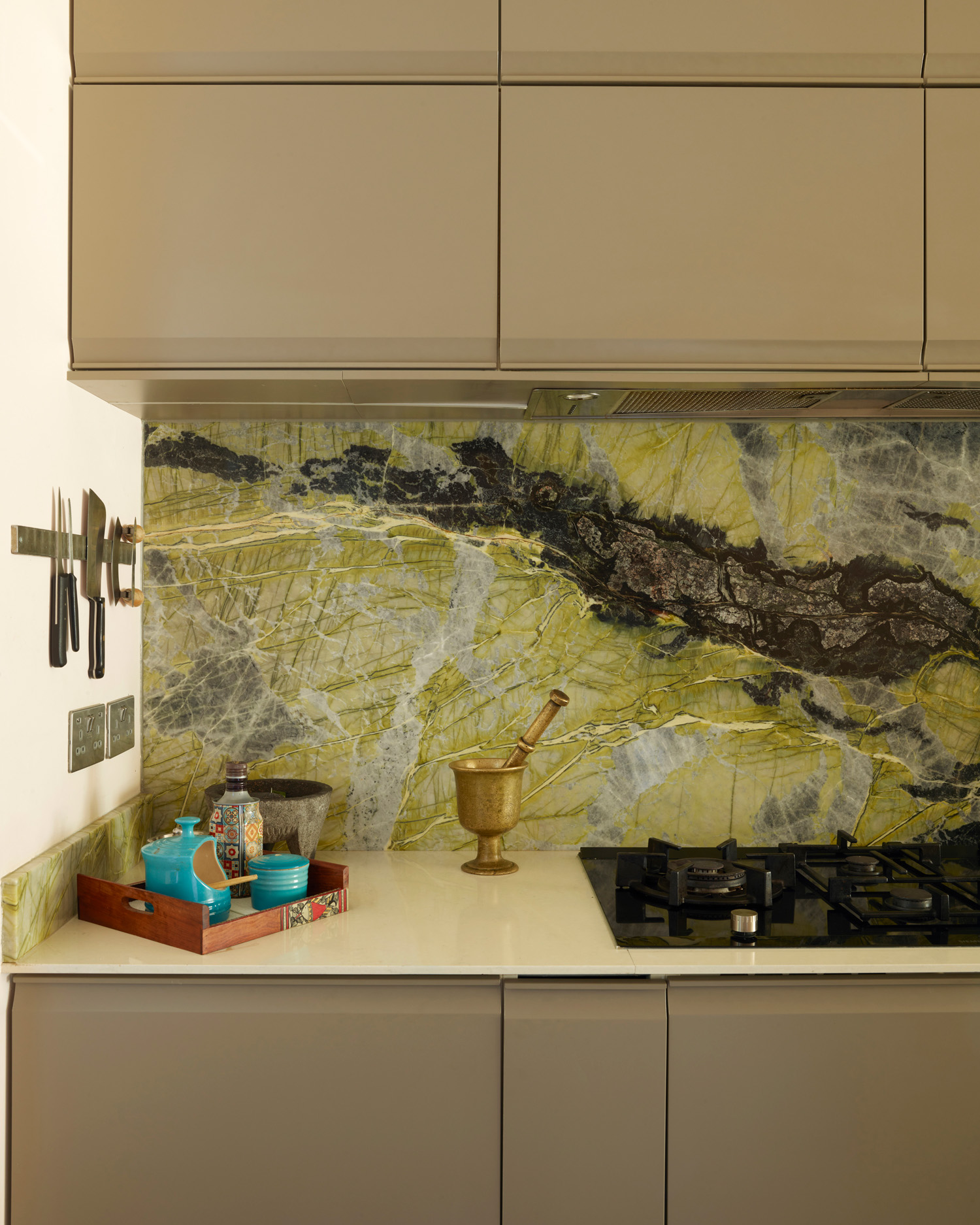 a kitchen with green marble splashback, grey cabinets and a white work top