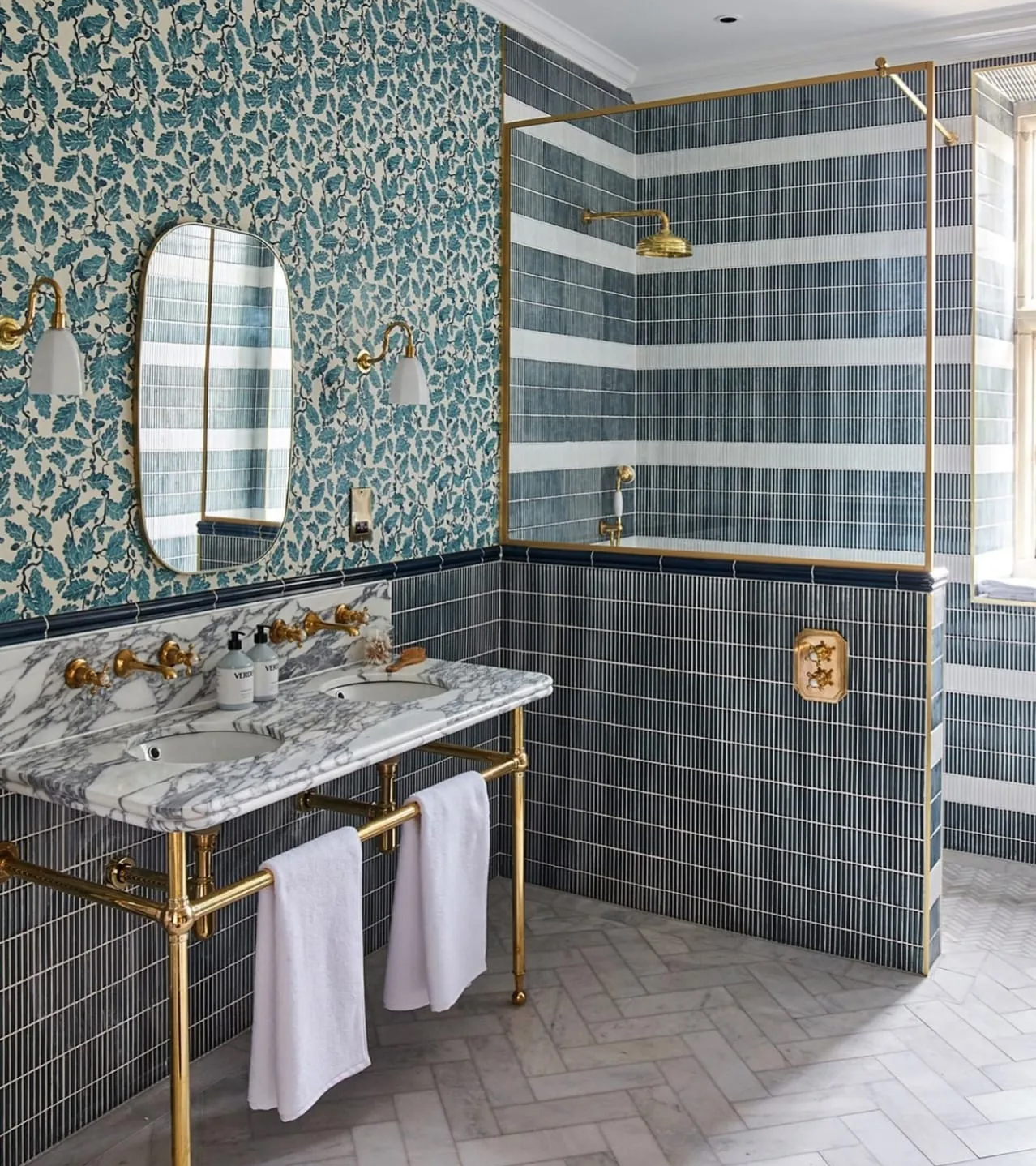 navy and white tiled ensuite with brass hardware and a marble sink