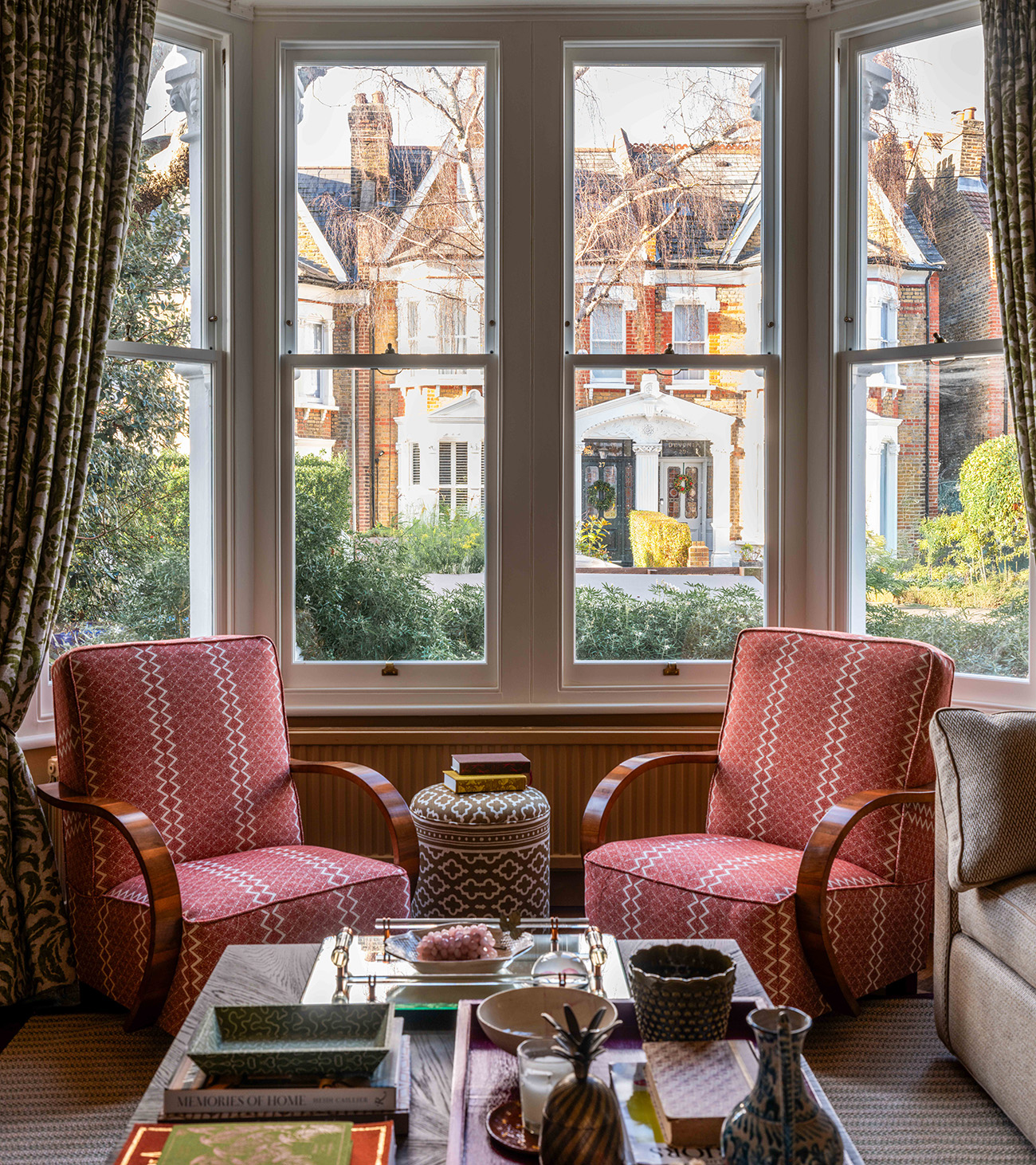 a bay window in a living room with two red patterned arm chairs facing eachother