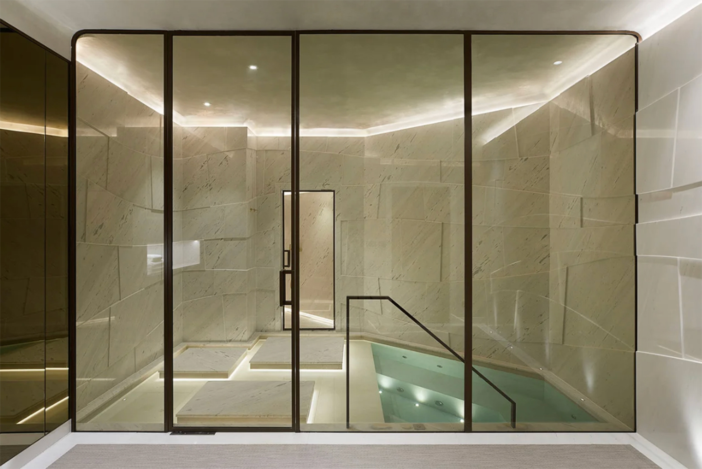 a modern luxury indoor plunge pool with black framed glass doors