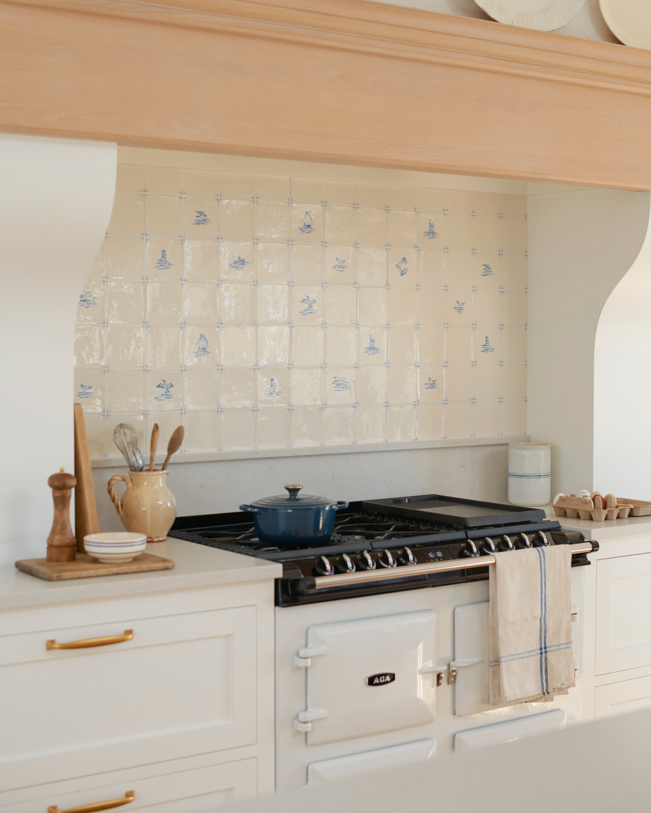 a white aga with a peach pink hood and blue and white delt tiles behind