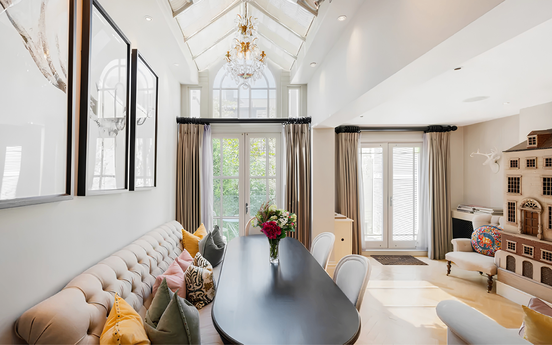 a dining room in a knightsbridge townhouse with a skylight, chandelier and a long black dining table